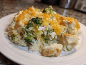 A close-up serving of creamy chicken and broccoli rice casserole topped with melted cheddar cheese.