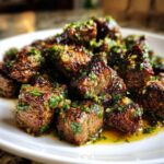 Close-up of perfectly seared steak bites coated in a glistening garlic herb butter sauce.