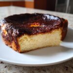 A close-up slice of creamy basque cheesecake with a signature dark, caramelized top.