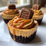 A close-up of one of the amazing cookie butter cheesecake cups, featuring a dark crust, light brown filling, caramel drizzle, and cookie topping.