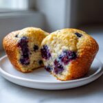 A cottage cheese blueberry muffin cut in half showing the moist interior packed with juicy blueberries.