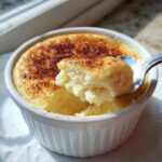 A spoonful of fluffy, baked 1 egg custard is lifted from a white ramekin, showing a caramelized top.