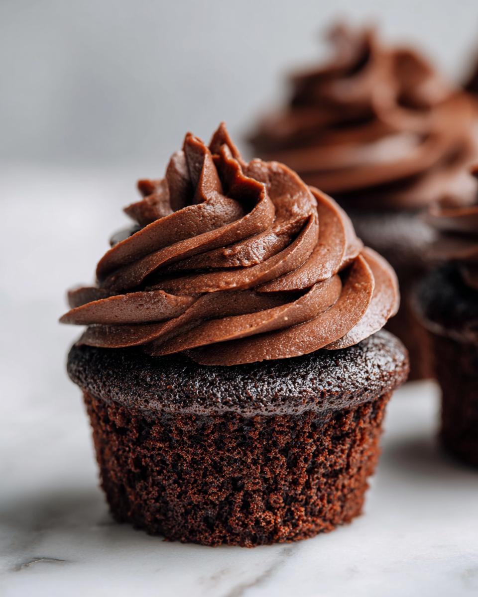 Close-up of a moist chocolate cupcake topped with a swirl of rich, dark chocolate frosting.