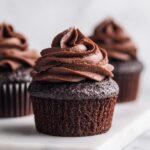 Close-up of a moist chocolate cupcake topped with a perfect swirl of dark chocolate frosting.