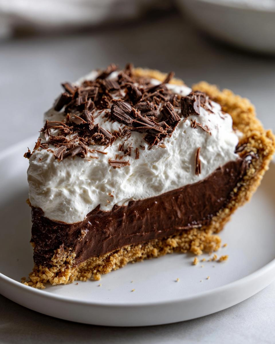 A perfect slice of chocolate cream pie featuring a thick chocolate filling, whipped cream, and chocolate shavings.