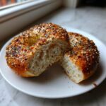 A sourdough discard bagel cut in half showing the airy interior and everything bagel seasoning crust.