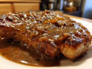 Close-up of a perfectly cooked, tender pork steak smothered in a thick, savory brown sauce with visible onion pieces.