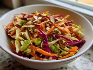 Close-up of a colorful cabbage salad featuring shredded green and red cabbage, carrots, and topped with sliced almonds.