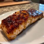 A perfectly cooked fillet of baked honey garlic salmon with a thick, caramelized, glossy glaze on top.