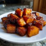Close-up of caramelized Brown Sugar Roasted Butternut Squash cubes piled on a white plate.
