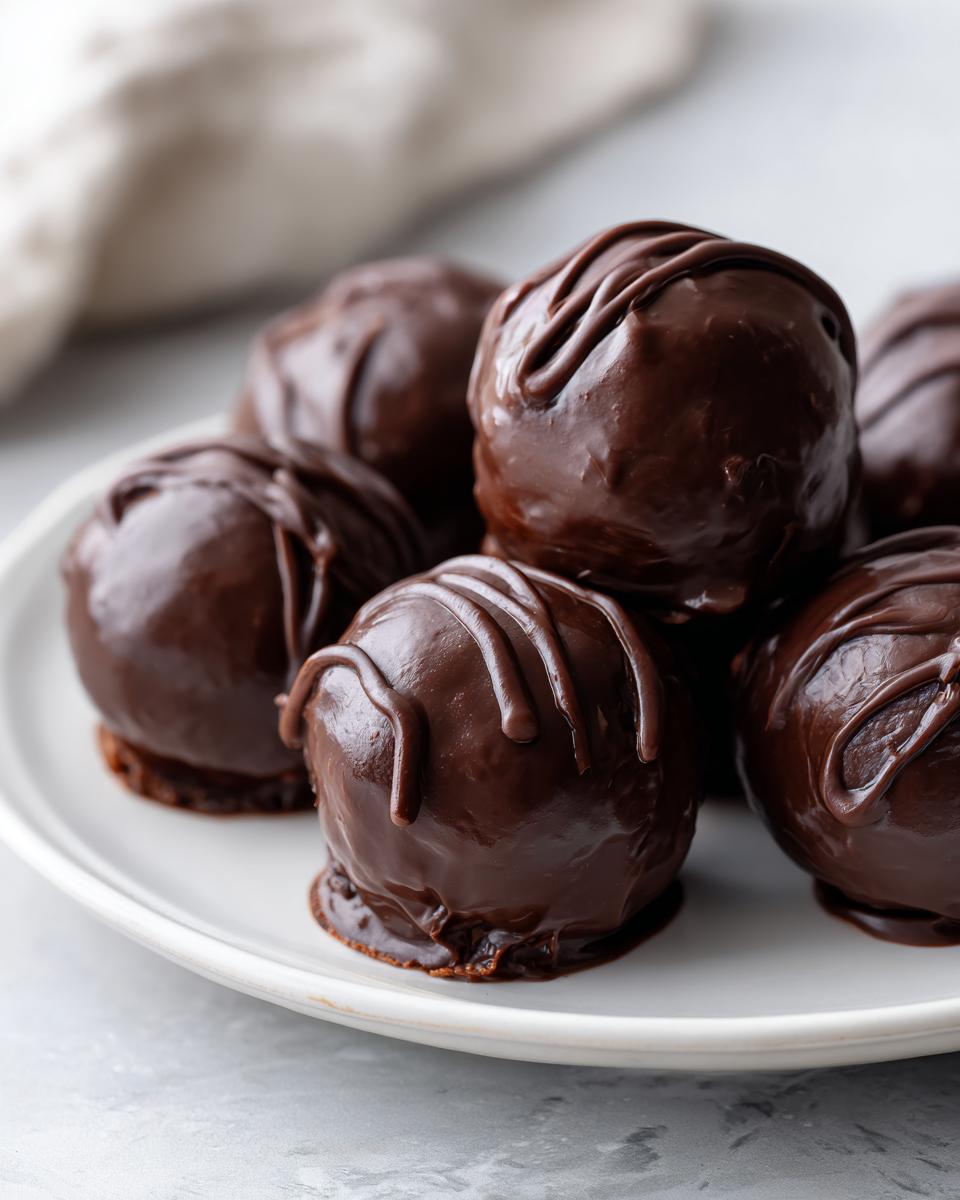 A plate of rich, dark chocolate coated oreo balls, drizzled with extra chocolate ganache.