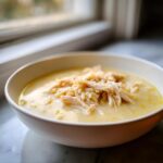 Close-up of a creamy bowl of Classic Greek Lemon Chicken Soup topped with shredded chicken and orzo pasta.