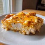 A close-up serving of Cream Cheese Chicken Bake showing moist white chicken topped with melted orange cheddar cheese and herbs.