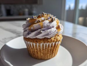 A single lavender honey cupcake with light purple frosting, drizzled with honey and topped with dried lavender buds.
