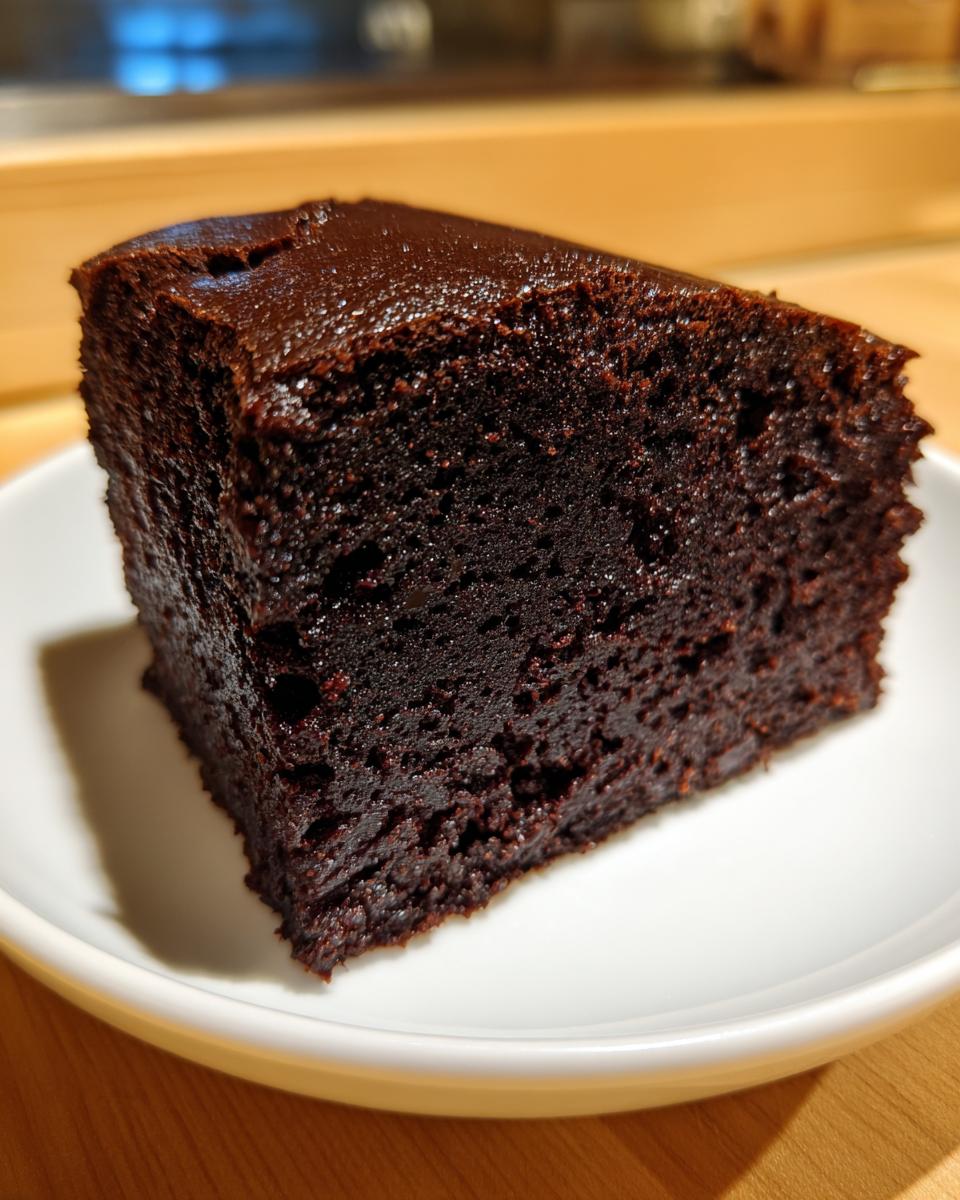 Close-up of a dense, fudgy slice of zero sugar brownies served on a small white plate.