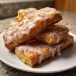 A close-up stack of golden brown, rectangular maple bars generously topped with a thick, white glaze.