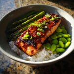 Close-up of a perfectly cooked honey glazed salmon bowl served over white rice with bright green asparagus and edamame.