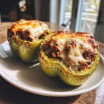 Two perfectly baked Keto Stuffed Bell Peppers, halved and filled with meat mixture, topped with bubbly, browned cheese.