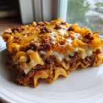 A close-up shot of a hearty serving of Frito Pie Casserole featuring layers of pasta, seasoned ground meat, and melted cheddar cheese.