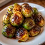 A close-up of roasted Brussels sprouts generously coated in a rich, Sticky Brussels Sprouts Glaze.