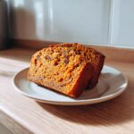 Two moist slices of Sweet Potato Cinnamon Bread featuring visible raisins, served on a small plate.