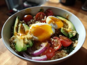 A vibrant avocado egg quinoa bowl featuring sliced avocado, poached eggs with runny yolk, cherry tomatoes, and red onion.