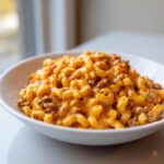 A close-up of a white bowl filled with creamy, cheesy homemade hamburger helper mixed with ground beef and elbow macaroni.