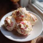 Four scoops of creamy lobster crab butter bombs mixed with visible red pieces of seafood on a white plate.